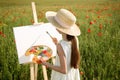 Little girl painting on easel in poppy field Royalty Free Stock Photo