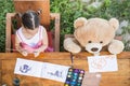 Little girl painting outdoor with her teddy bear friend Royalty Free Stock Photo