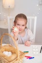 Girl paints eggs edible markers. Easter traditions