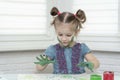 Little girl paints with fingers