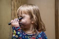 A little girl paints her face with a felt-tip pen in front of a mirror, a young makeup artist. Concept: childlike spontaneity Royalty Free Stock Photo