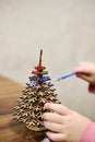 A little girl paints a wooden toy in the shape of a Christmas tree. Children's leisure Royalty Free Stock Photo