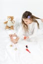 Little girl in pajamas and curlers applying nail polish to toenails sitting on bed Royalty Free Stock Photo