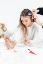 Little girl in pajamas and curlers applying nail polish to toenails sitting on bed Royalty Free Stock Photo