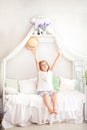 A little girl in pajamas enjoys a sunny morning and stretches herself in bed. Good morning at home. The child wakes up from a drea Royalty Free Stock Photo