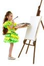 Little girl with a palette and brush near the easel.