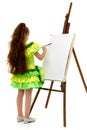 Little girl with a palette and brush near the easel.