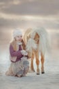 Little girl with palomino miniature horse in winter park Royalty Free Stock Photo