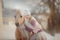 Little girl with palomino miniature horse in winter park