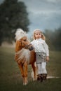 Little girl with palomino miniature horse in summer day