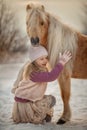 Little girl with palomino pony in winter park Royalty Free Stock Photo