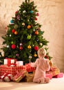 Little girl with parcels round Christmas tree