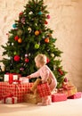 Little girl with parcels round Christmas tree