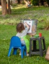 Little girl in the park draws with paints