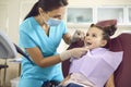 Little girl at a pediatric dentist with mask and gloves service child tooth care in a dental dentistry clinic.