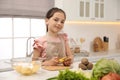 Little girl peeling potato at table. Preparing vegetable