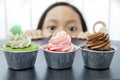 Little girl is peeping tasty cupcakes Royalty Free Stock Photo