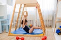 Little girl performs gymnastic exercises on a wooden home sports complex Royalty Free Stock Photo