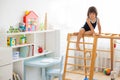 Little girl performs gymnastic exercises on a wooden home sports complex Royalty Free Stock Photo