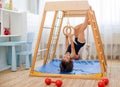 Little girl performs gymnastic exercises on a wooden home sports complex Royalty Free Stock Photo