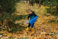 Little girl picking up piece trash in a seasonal forest at autumn