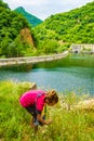 Little girl picks dry flowers at mountain reservoir edge Bulgaria