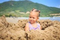 Little Girl with Pigtail in Swimsuit Sits on Sand Beach