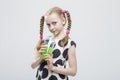 LIttle Girl With Pigtails Posing in Polka Dot Dress with Cup of Green Juice.