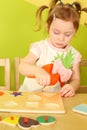 Little girl with pigtails puts wooden geometric