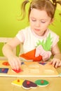 Little girl with pigtails puts wooden geometric