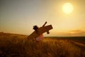 Little girl in pilot`s suit in field on nature at sunset.