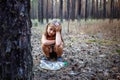 Little girl in the pine forest near the plastic bottle.