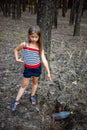 Little girl in the pine forest near the plastic bottle.