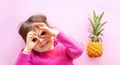 Little girl and pineapple on a pink background Royalty Free Stock Photo
