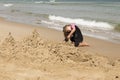 Little girl in pink and black wetsuit making sand castles Royalty Free Stock Photo