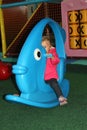 little girl in pink coat swinging on a blue toy in the form of f Royalty Free Stock Photo