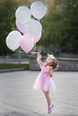 Little girl in pink dress with balloons jumping on the street Royalty Free Stock Photo