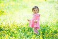 A little girl in a pink dress is laughing in a clearing with dandelions. Royalty Free Stock Photo