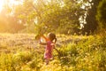 Little girl in pink dress picking fresh apples growing on apple tree in summer field Royalty Free Stock Photo