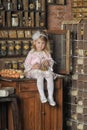 Little girl in a pink dress sitting on retro kitchen Royalty Free Stock Photo