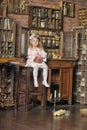 Little girl in a pink dress sitting on retro kitchen Royalty Free Stock Photo