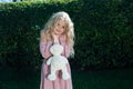 Little girl in a pink dress with a soft rabbit toy