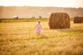 Baby girl pink dress stand on stack wheat field