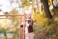 Funny portrait of a little girl. Little girl in a pink hat on a walk in the fall. Child girl in a jacket happily runs and collects