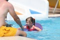 Little girl in pink lifebuoy swims to her father in the pool of water park Royalty Free Stock Photo