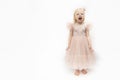 Little girl in pink lush dress is screaming . Cute girl in elegant dress and bare feet isolated on white background. Capricious