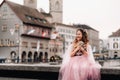 A little girl in a pink Princess dress with a bouquet in her hands walks through the old city of Zurich.Portrait of a girl in a Royalty Free Stock Photo