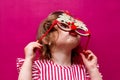 A little girl in a pink striped dress with Christmas tree-shaped glasses. The girl's very surprised festive face