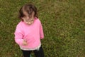 A little girl in a pink T-shirt holds a dandelion in her hands while standing on the lawn. View from above Royalty Free Stock Photo