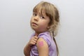 A little girl with a pink tattooed QR code on her shoulder, light background. Concept: assignment of a QR code, people with antibo